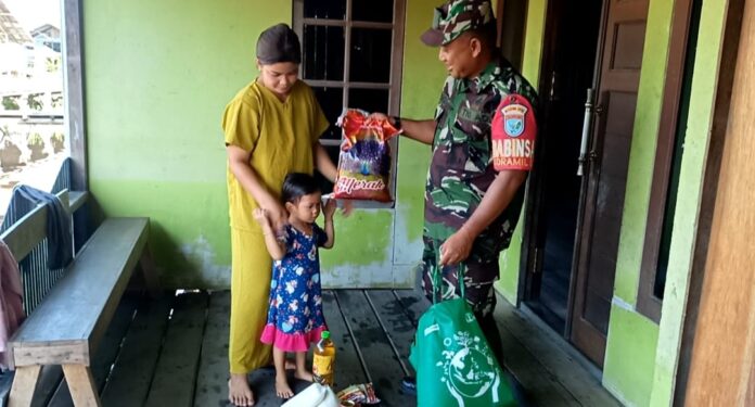 BAGIKAN SEMBAKO : Babinsa Kelurahan Petuk Katimpun, Pelda Nurkholis ketika membagikan sembako, Minggu (9/4/2023). (foto:supri)